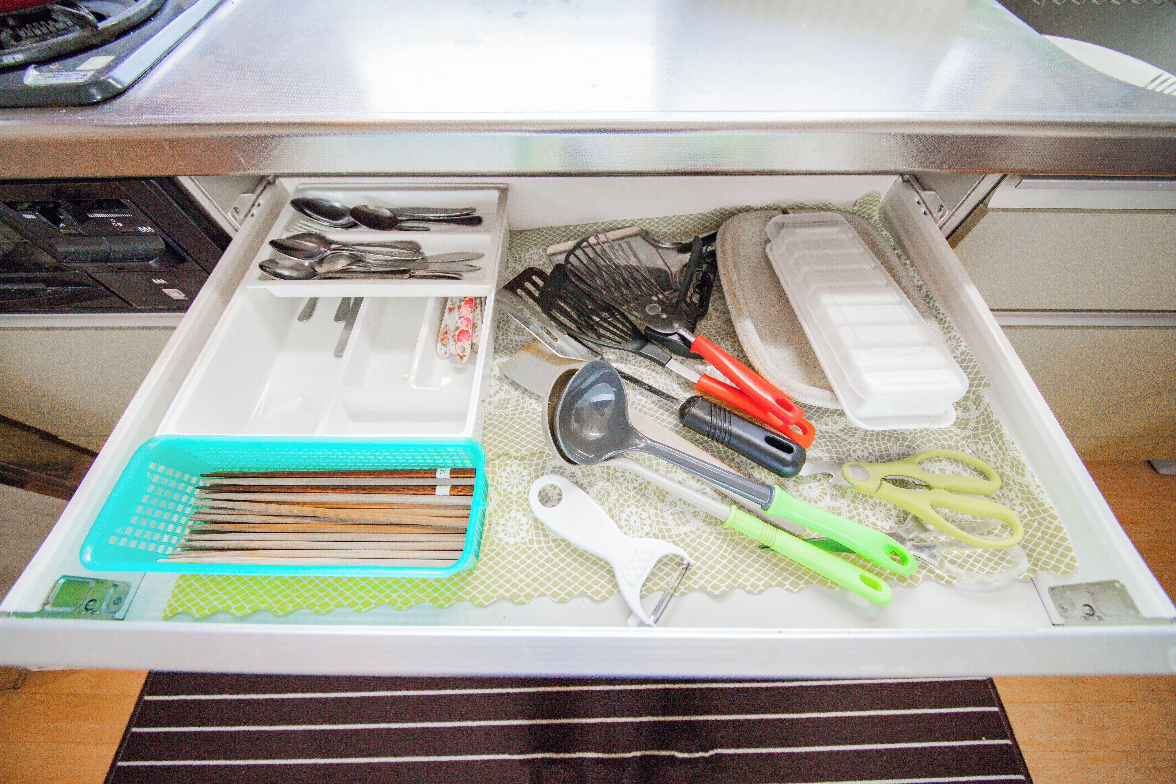 A kitchen drawer with utensils, a whisk, a spatula, and a cutting board.