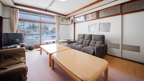Ein Wohnzimmer mit einer Couch, einem Fernseher, einem Tisch und Blick auf Schnee.