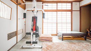 Ein Zimmer mit Tatami-Boden, einer Klimmzugstange, einem Massagetisch und einem Fenster mit traditionellen Shoji-Bildschirmen.
