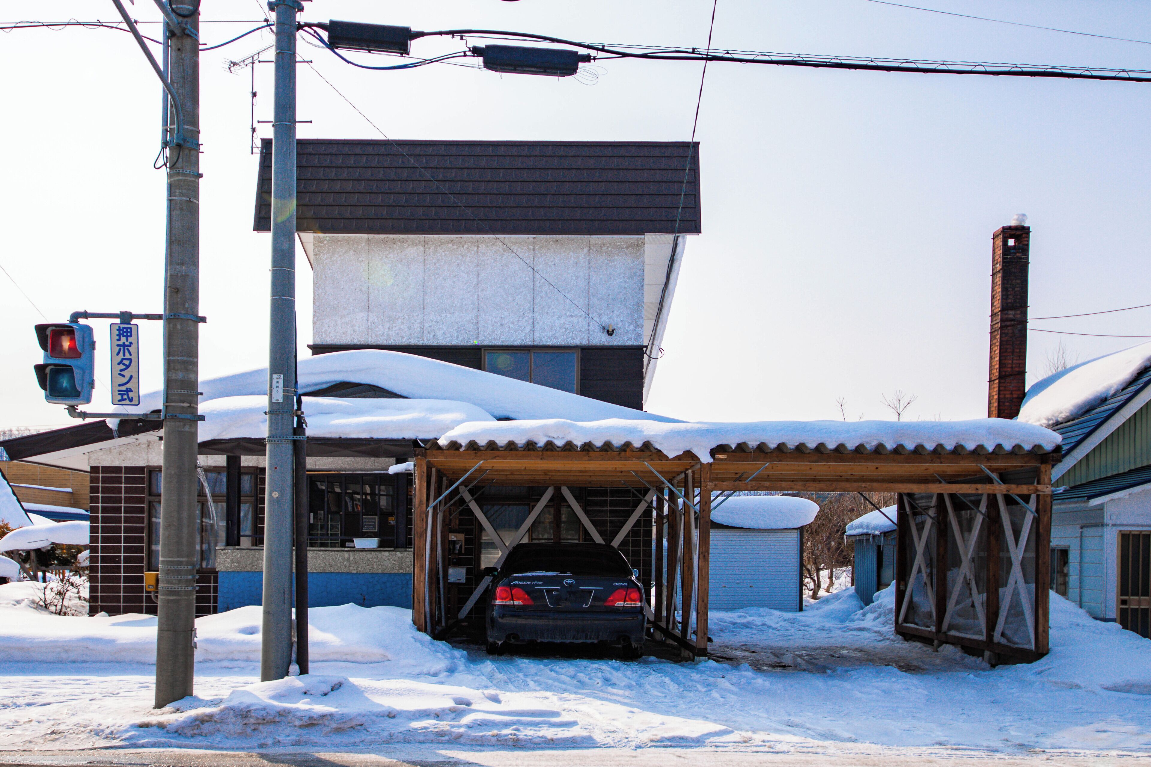 A car parked under a covered area with a building in the background.