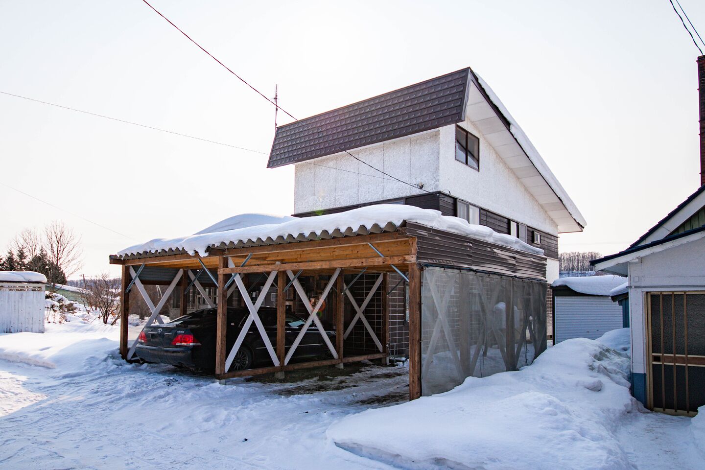 Une maison à deux étages avec une voiture garée sous un garage fermé.