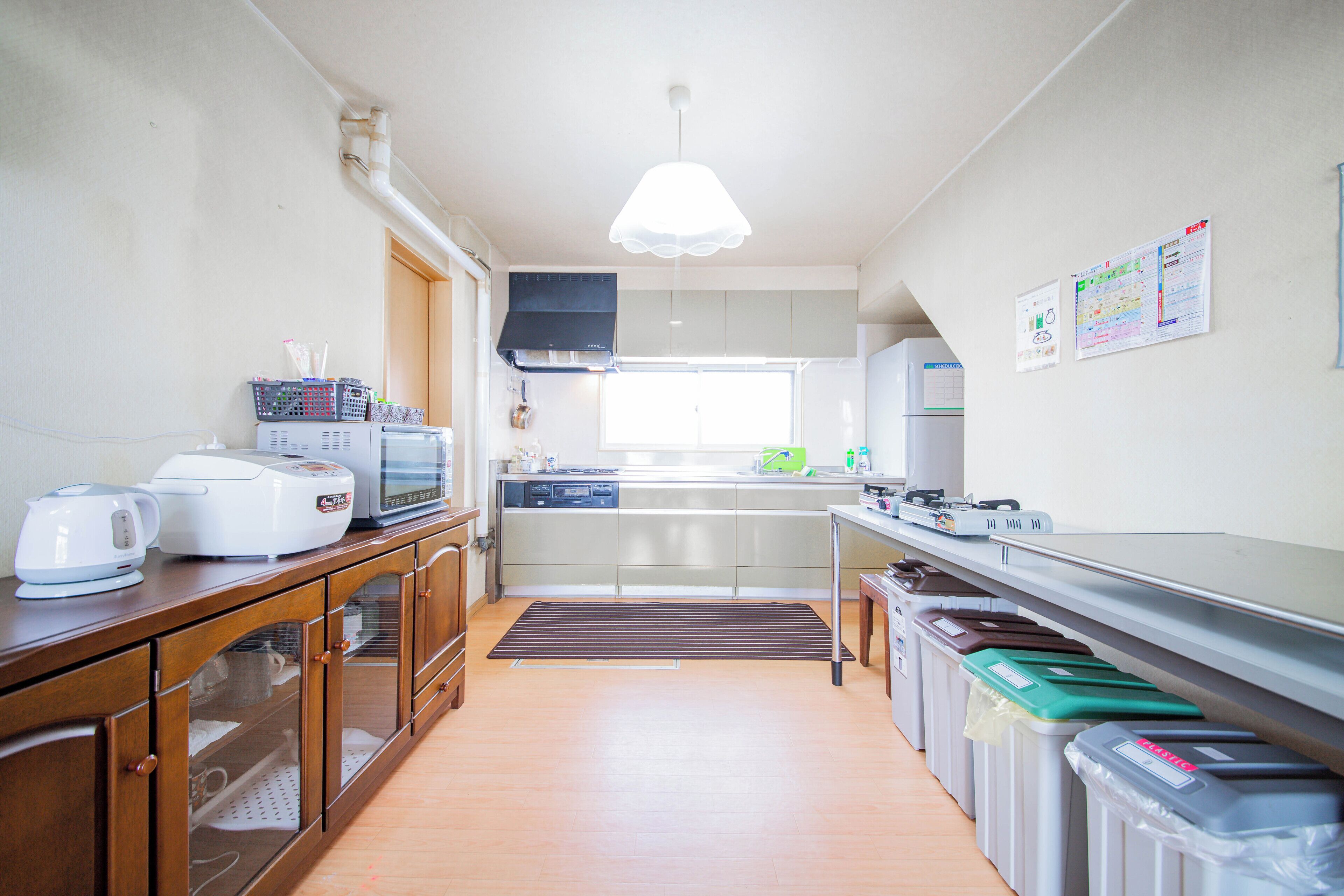 A modern kitchen with a microwave, toaster, and kettle on the counter, a sink, and a window above the sink.
