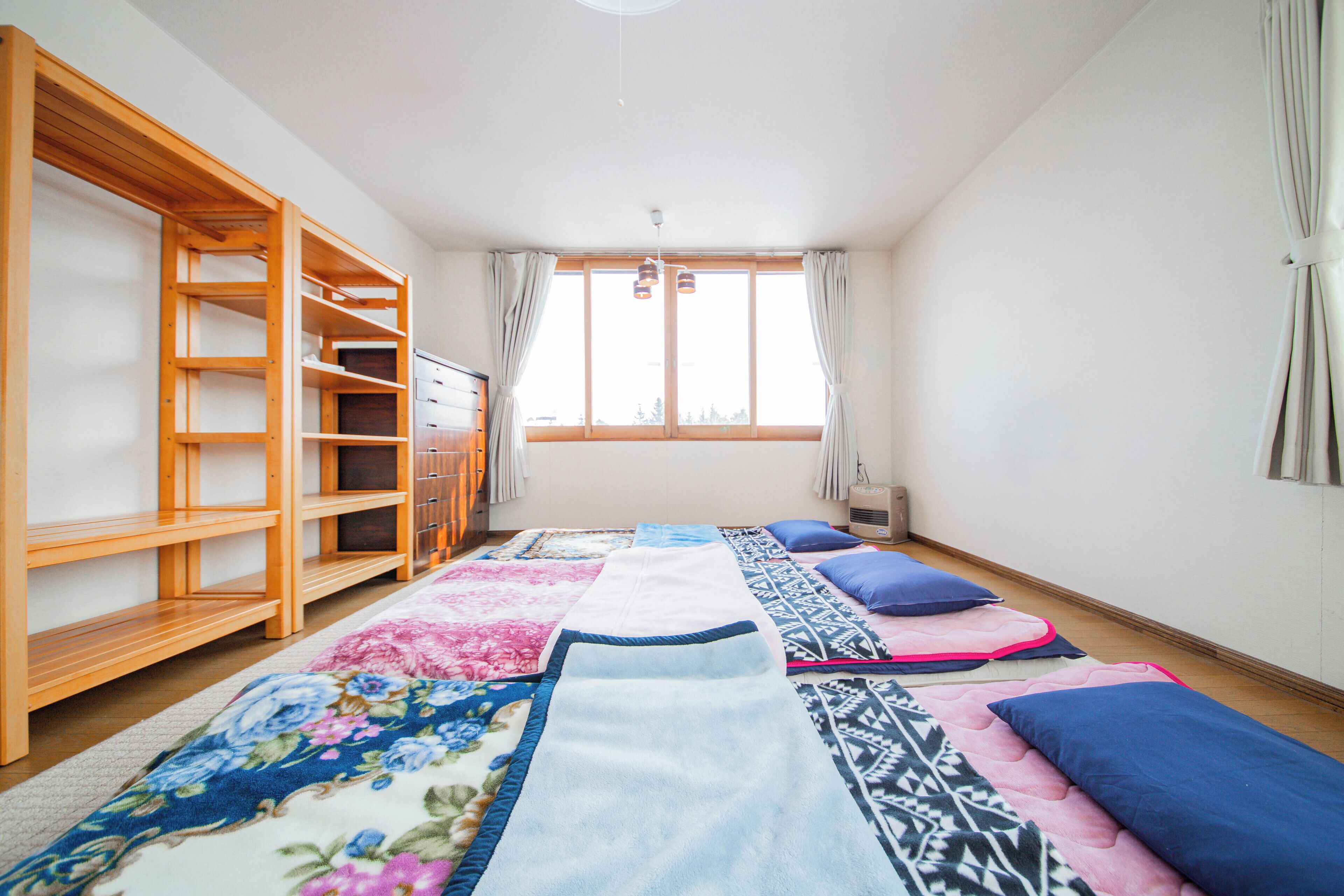 A room with a bed, a wooden wardrobe, and a window with curtains.