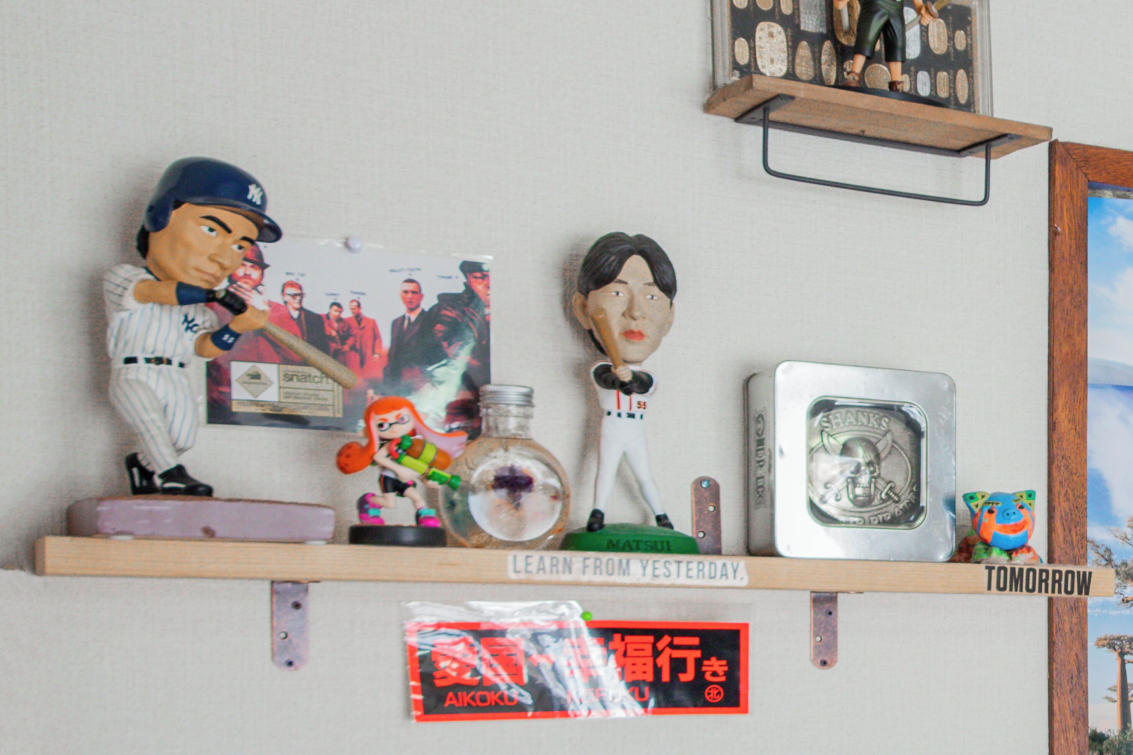 Une étagère contenant divers objets, notamment des figurines, un tableau encadré et un petit jouet.