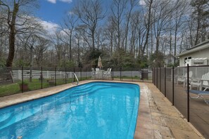 Una piscina rectangular con borde de azulejos, rodeada por una terraza de piedra.