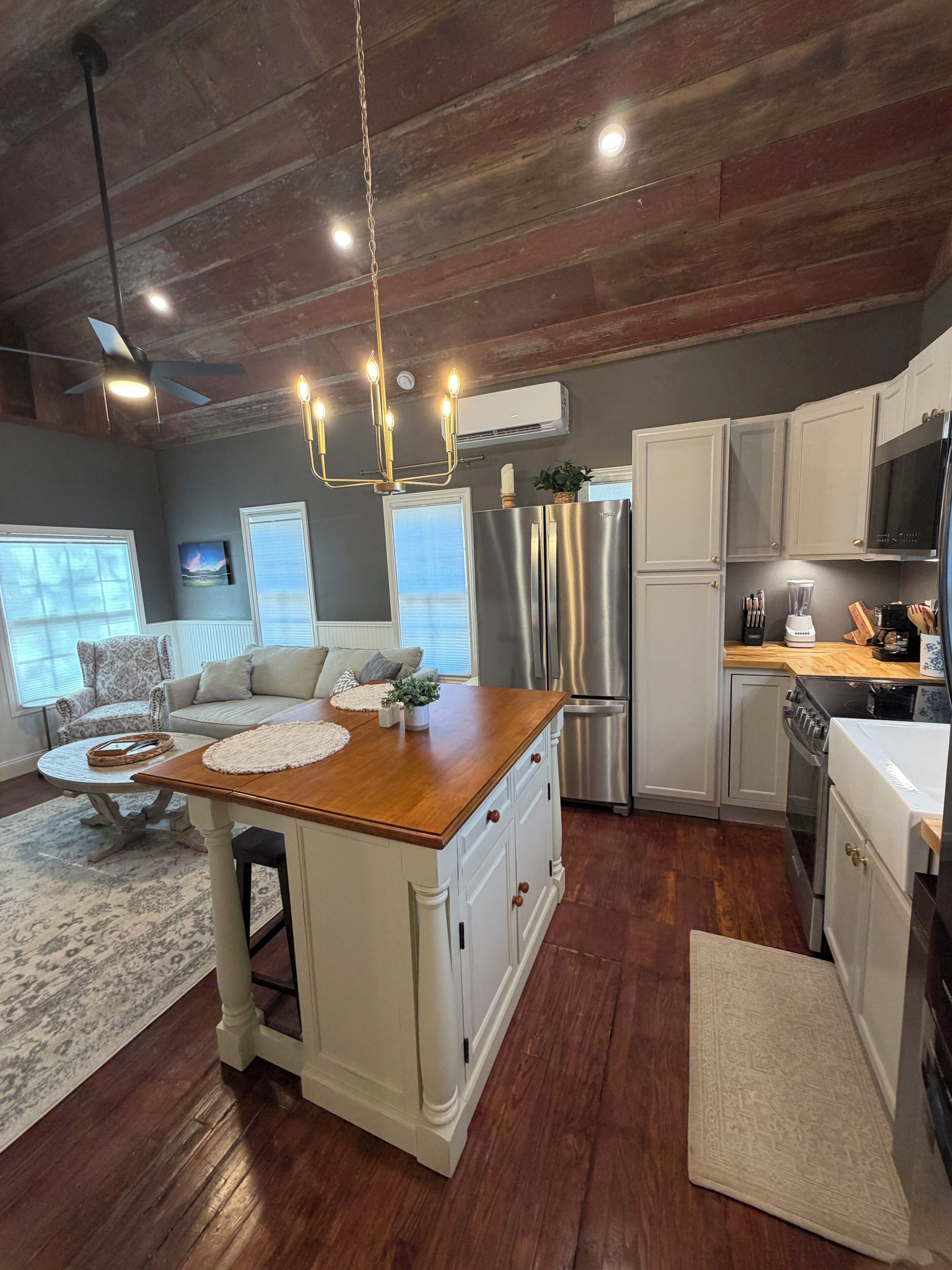 A modern kitchen with a central island, stainless steel appliances, and a dining area with a sofa and coffee table.