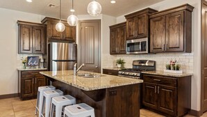 A modern kitchen with dark wood cabinets, stainless steel appliances, and a large island with bar stools.
