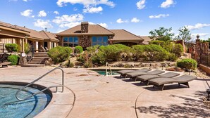 A residential property with a swimming pool, lounge chairs, and a stone facade.