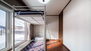 Ein Zimmer mit Etagenbett, einem Fenster mit Blick auf eine verschneite Landschaft und Holzboden.