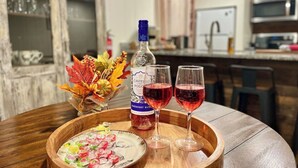 Una mesa de madera con una botella de vino Castello del Poggio, dos copas de vino tinto y un plato de comida colorida.