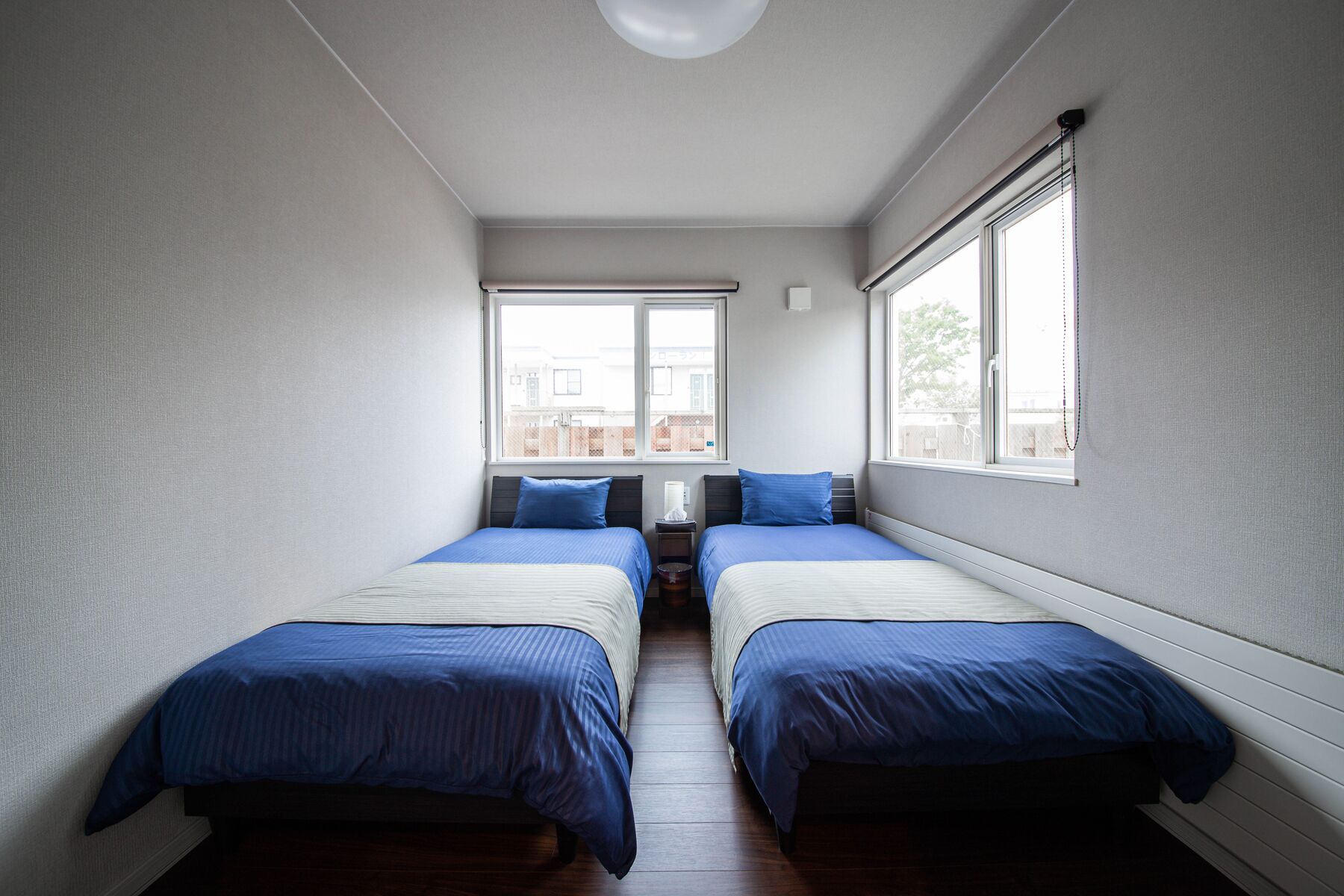 A room with two beds, a window, and a ceiling light.