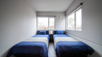 A room with two beds, a window, and a ceiling light.
