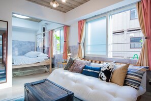 A modern bedroom with a bunk bed, a sofa with patterned cushions, and a bedside table with a lamp. - CLASSE TROIS (Sapporo)