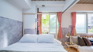 A modern bedroom with a large bed, bedside tables, and a view of greenery outside. - CLASSE TROIS (Sapporo)