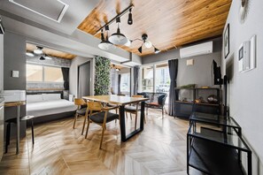 Un interior moderno con zona de comedor, un sofá y un amplio ventanal.