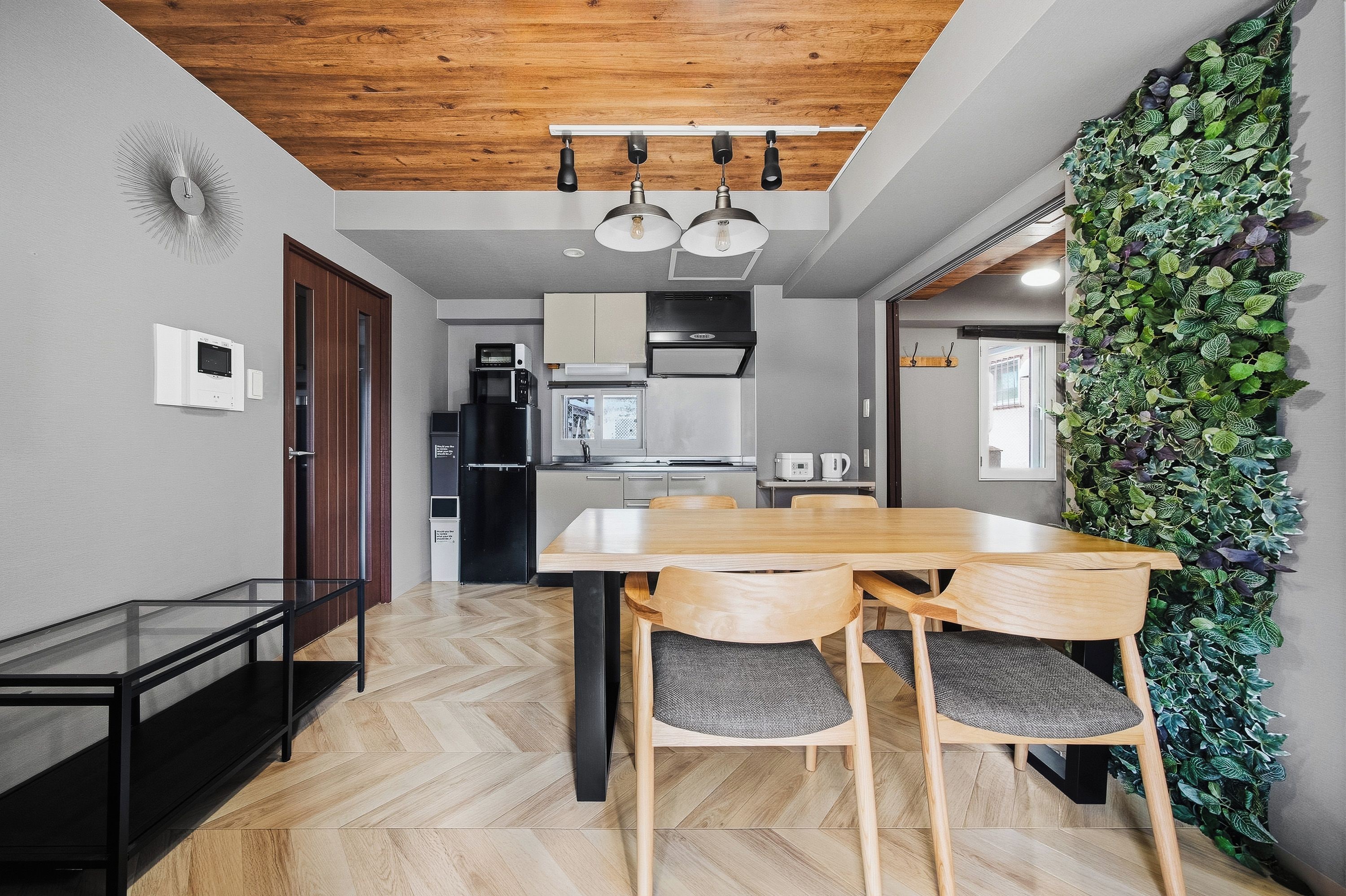 Cozinha moderna com teto de madeira, mesa de jantar com cadeiras e um jardim vertical na parede.