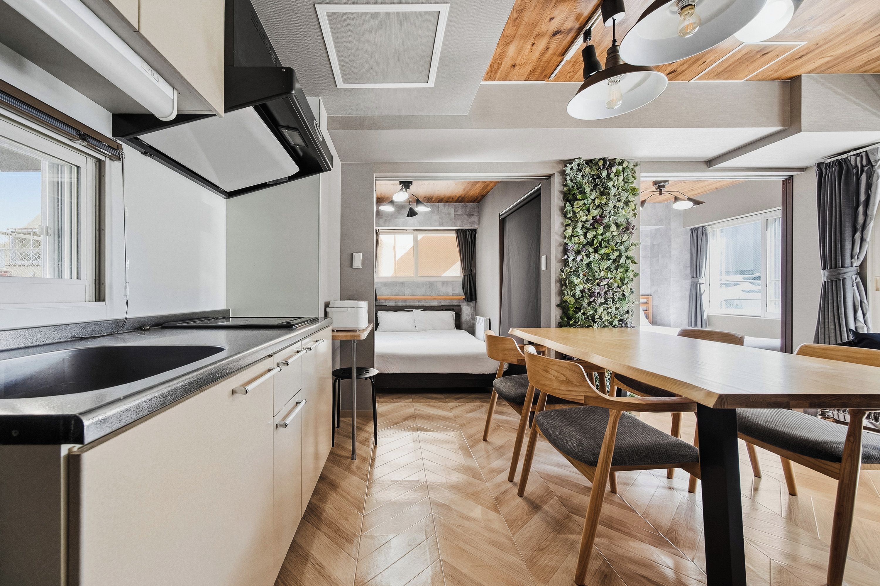 A compact kitchen with a built-in stove, a dining area with a wooden table and chairs, and a view through a window.