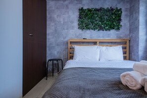 A bedroom with a bed, a wooden headboard, a small stool, and a wall-mounted plant. - CLASSE CINQ (Sapporo)