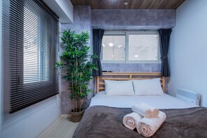 A modern bedroom with a large bed, a potted plant, and a window with curtains. - CLASSE CINQ (Sapporo)
