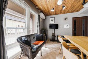 A modern interior with a wicker chair, a wooden dining table, and a flat-screen TV mounted on the wall. - CLASSE CINQ (Sapporo)