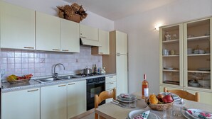 Uma cozinha compacta com área de jantar, equipada com comodidades básicas como pia, fogão e armários.