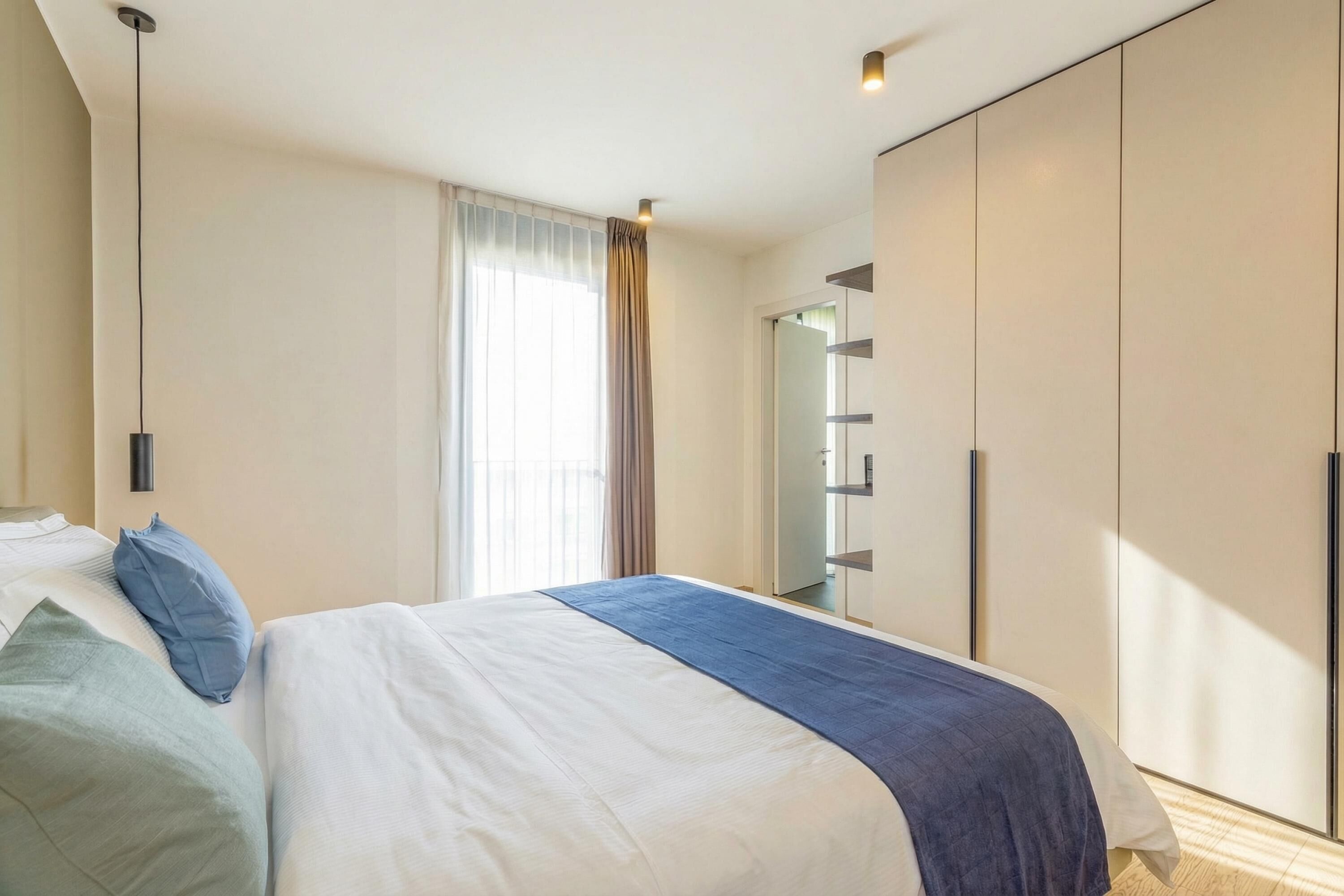 Une chambre d’hôtel moderne avec un grand lit, une armoire et un miroir.