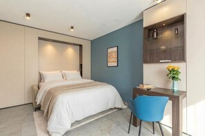 Um quarto moderno com uma cama, uma escrivaninha, uma cadeira e uma prateleira com objetos decorativos.