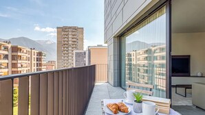 A balcony with a table set for breakfast, a plant, and a TV. - ICON H Lugano 402 Suite Business, Lugano, Switzerland (Lugano)