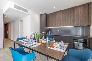 A modern dining area with a wooden table, blue chairs, and a built-in oven. - ICON H Lugano 401 Suite Business, Lugano, Switzerland (Lugano)