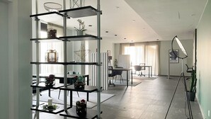 A modern interior with a multi-tiered metal shelving unit, a dining area with a table and chairs, and a studio lighting setup. - ICON H Lugano 306 Suite Micro-Living, Lugano, Switzerland (Lugano)