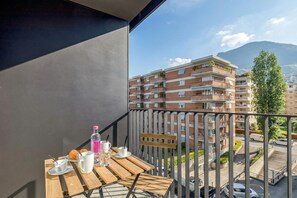 Ein Balkon mit einem Tisch für zwei Personen, einer Flasche und einer Tasse.