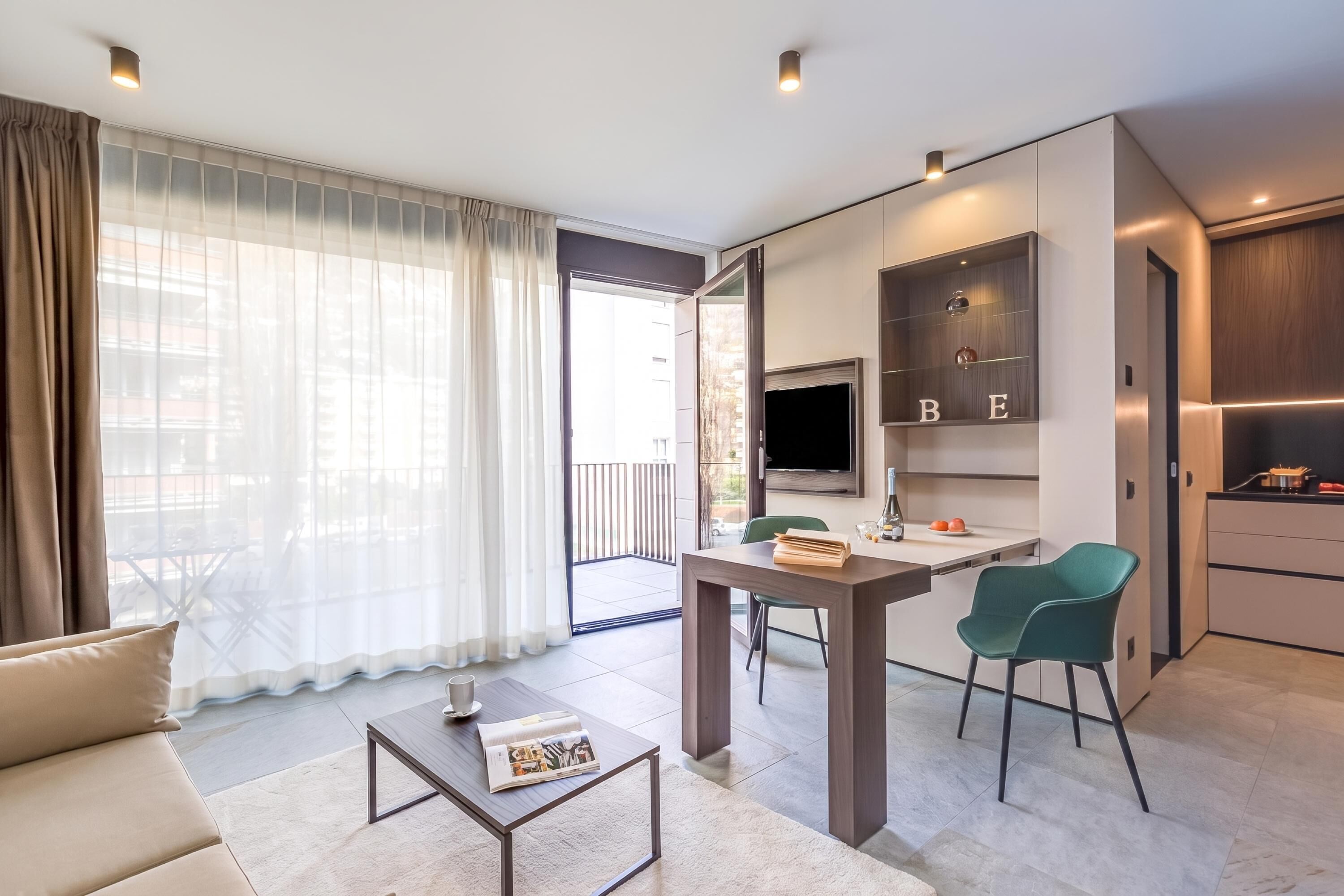 Un soggiorno moderno con un divano, un tavolino, una TV e un'area pranzo con sedie.