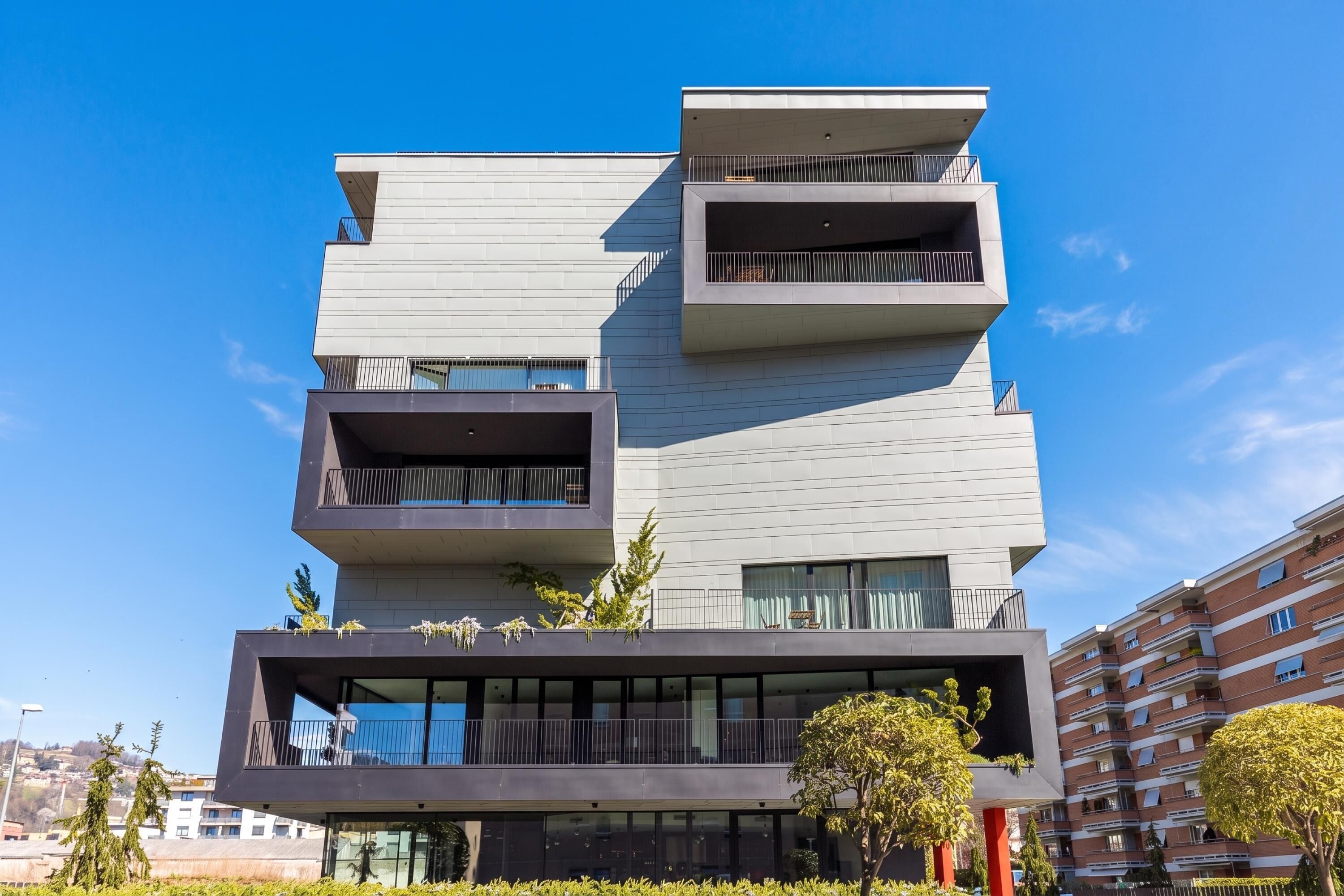 Een modern meerlaags gebouw met balkons, grote ramen en een plat dak.