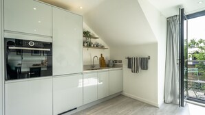 Una cocina moderna con armarios blancos, un horno Bosch y una ventana con vistas a zonas verdes.