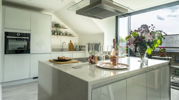 Cocina moderna con una isla grande, electrodomésticos integrados y vistas al exterior.