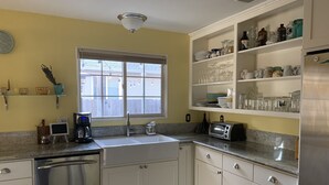 Eine Küche mit weißen Schränken, einem Edelstahl-Geschirrspüler, einer Kaffeemaschine und einem Toaster.