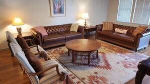 A living room with a brown leather sofa, a wooden coffee table, and a patterned rug.