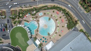 An aerial view of a resort with a central pool, sun loungers, and a landscaped area.