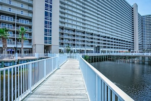 Un hotel frente al mar con un muelle de madera, varios balcones y un puerto deportivo.