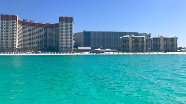 A beachfront hotel with high-rise buildings, a sandy beach, and clear turquoise water.