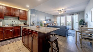 A modern kitchen with wooden cabinets, a central island, and a dining area with a table and chairs.