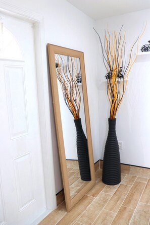 Reflect on the serene ambiance of this stylish space, featuring a large mirror and elegant vases.