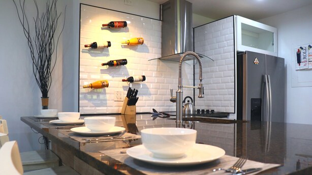 A modern kitchen with a stainless steel refrigerator, a wine rack, and a built-in microwave. - Perfect Escape From Home / Hogar Lejos De Casa (Miami)