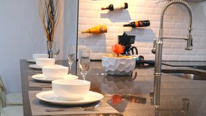 A kitchen counter with white bowls, glasses, and a decorative vase. - Perfect Escape From Home / Hogar Lejos De Casa (Miami)