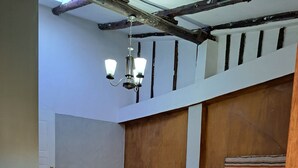 Una camera da letto con un letto in legno, un letto più piccolo nell'angolo, una panca di legno e un lampadario.