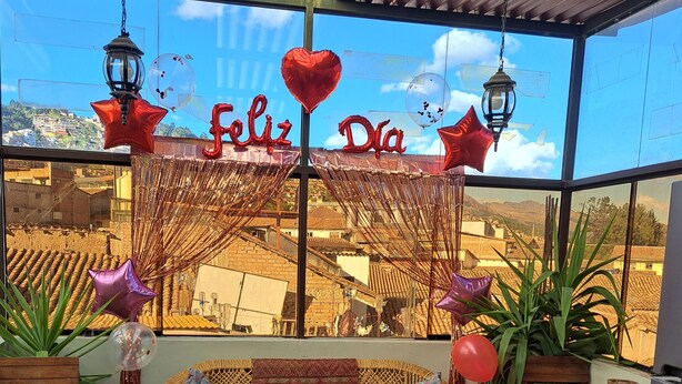 Un patio accogliente con un divano in vimini, un tappeto decorato e vista su una cittadina attraverso ampie finestre.