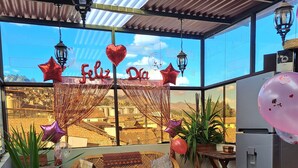 Un'accogliente zona con posti a sedere all'aperto, mobili in vimini, un frigorifero e palloncini decorativi.