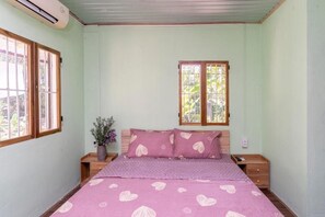 Un dormitorio con cama, mesita de noche, ventana y una planta en maceta.