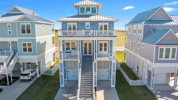 A multi-story house with a central staircase, a garage, and a driveway. - Family Friendly Beach House in Gated Beach Resort (Galveston)