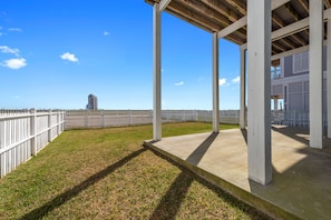 A covered outdoor area with a concrete floor, white wooden posts, and a white fence. - Family Friendly Beach House in Gated Beach Resort (Galveston)
